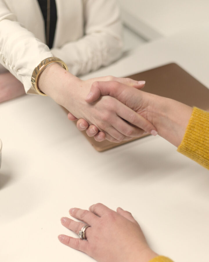 Two people shaking hands across a desk